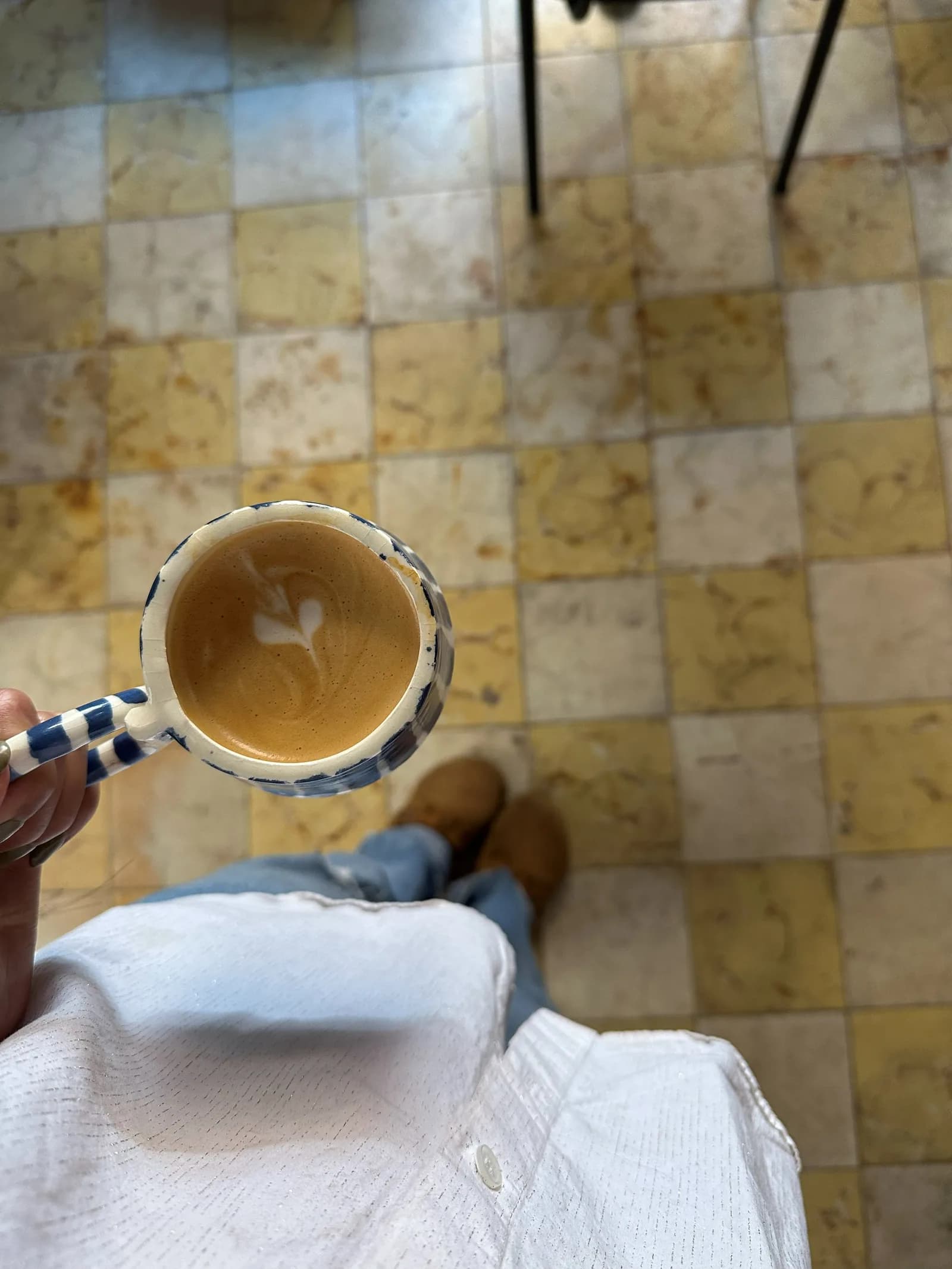 Manos sosteniendo una taza de cerámica con arte latte.